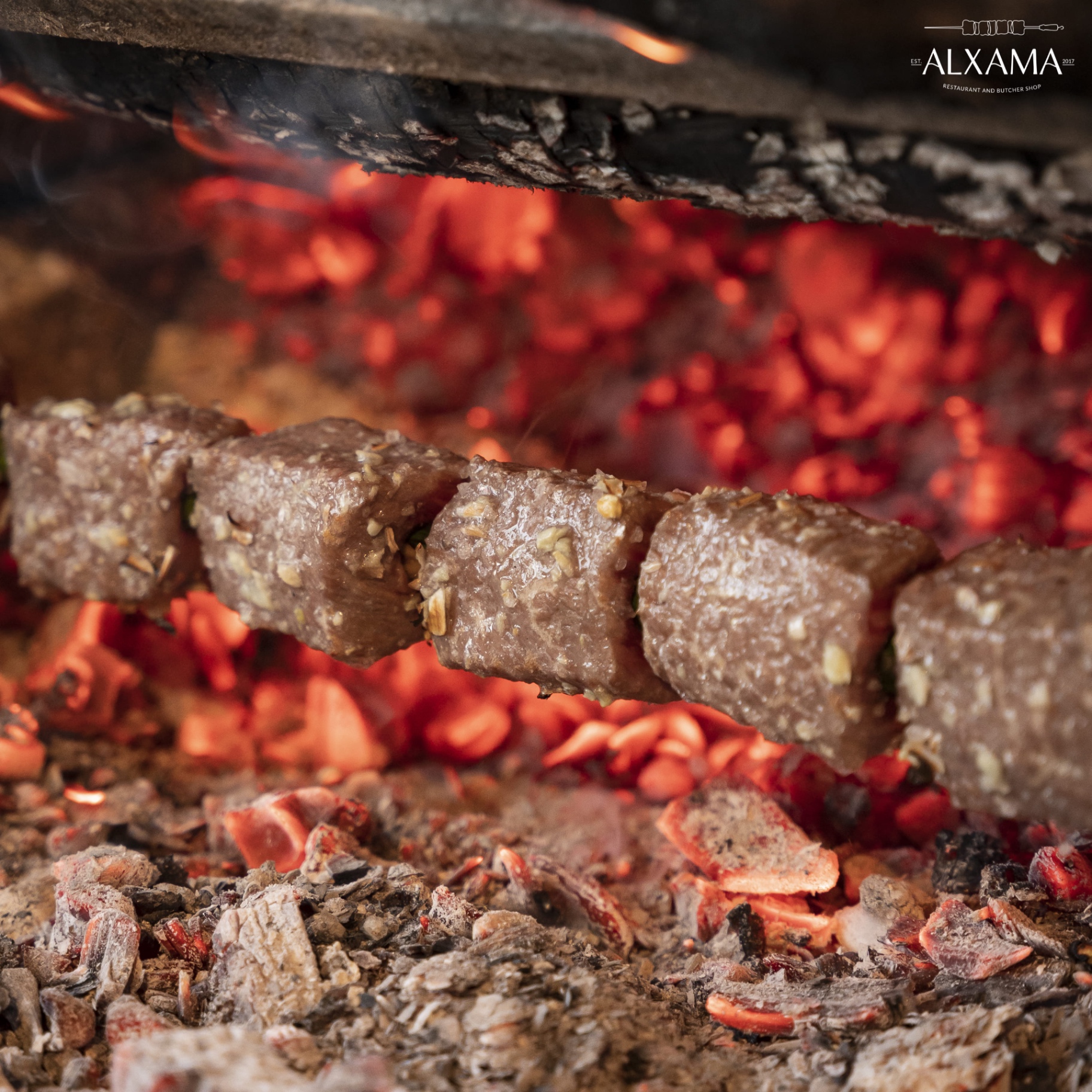 Grilled meat skewer suspended above the table at Alxama restaurant in Quarteira
